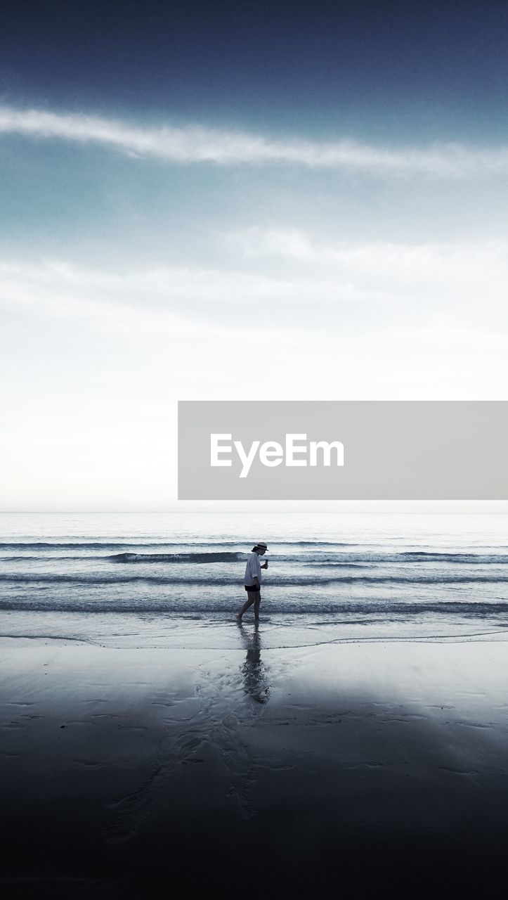 Woman walking at beach against sky