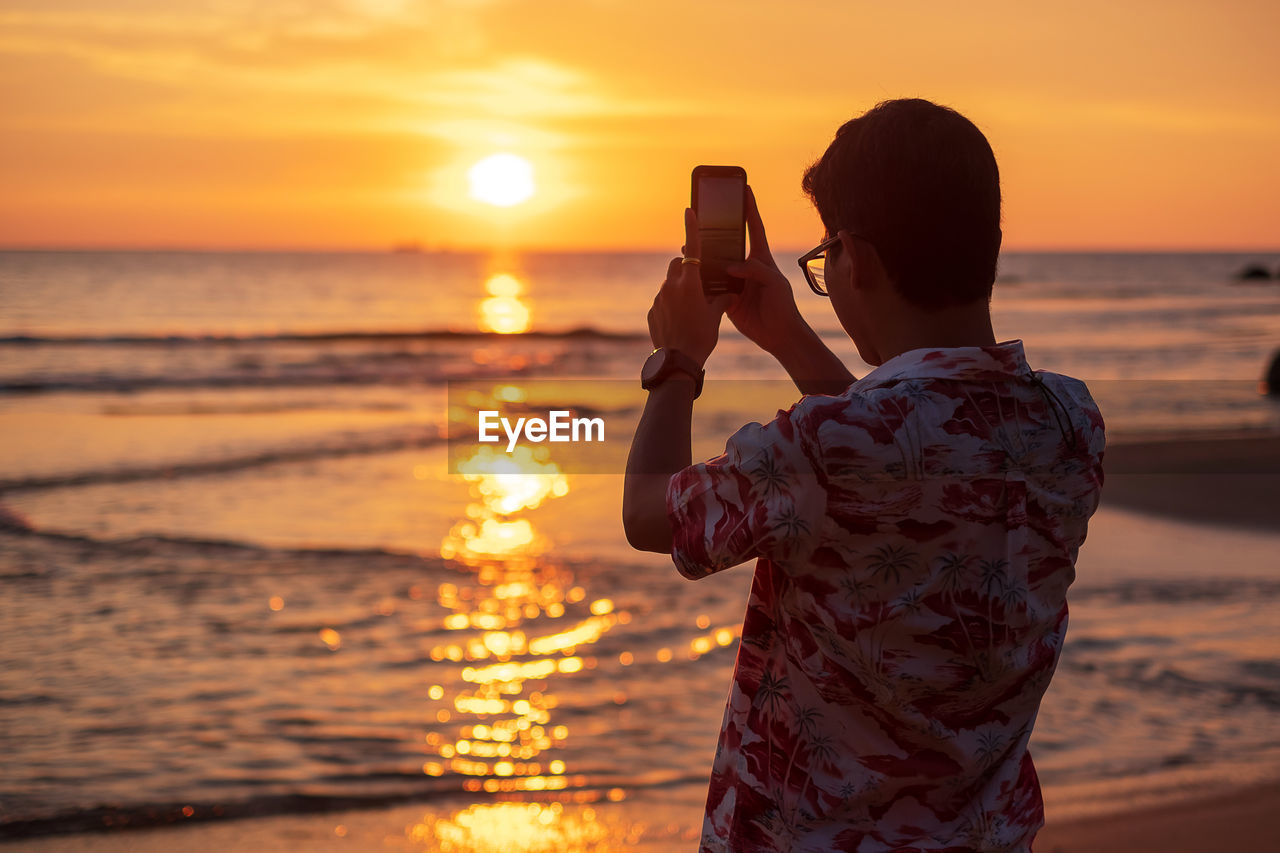 MAN PHOTOGRAPHING AT SUNSET