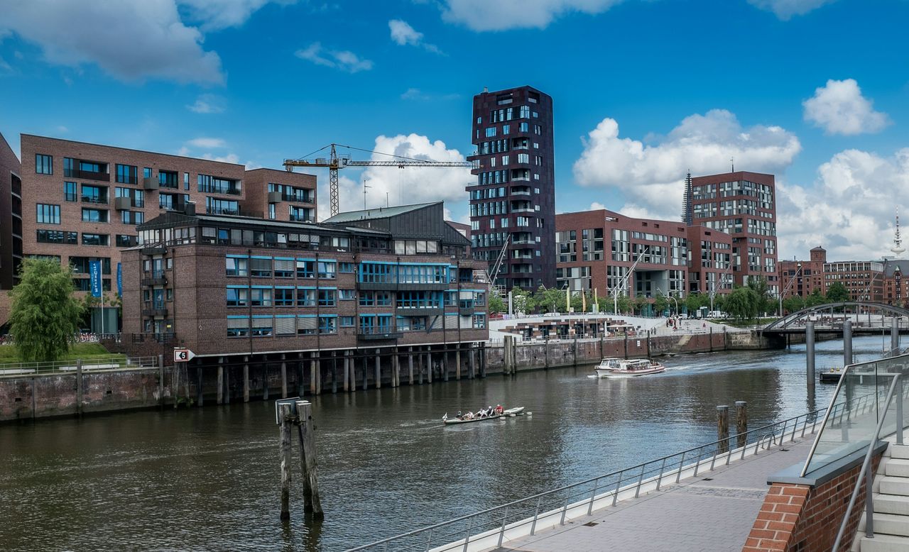 Buildings by river in city against sky