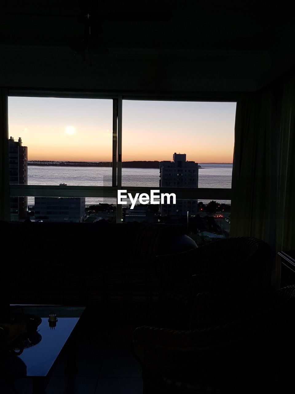 SCENIC VIEW OF SEA SEEN THROUGH WINDOW DURING SUNSET