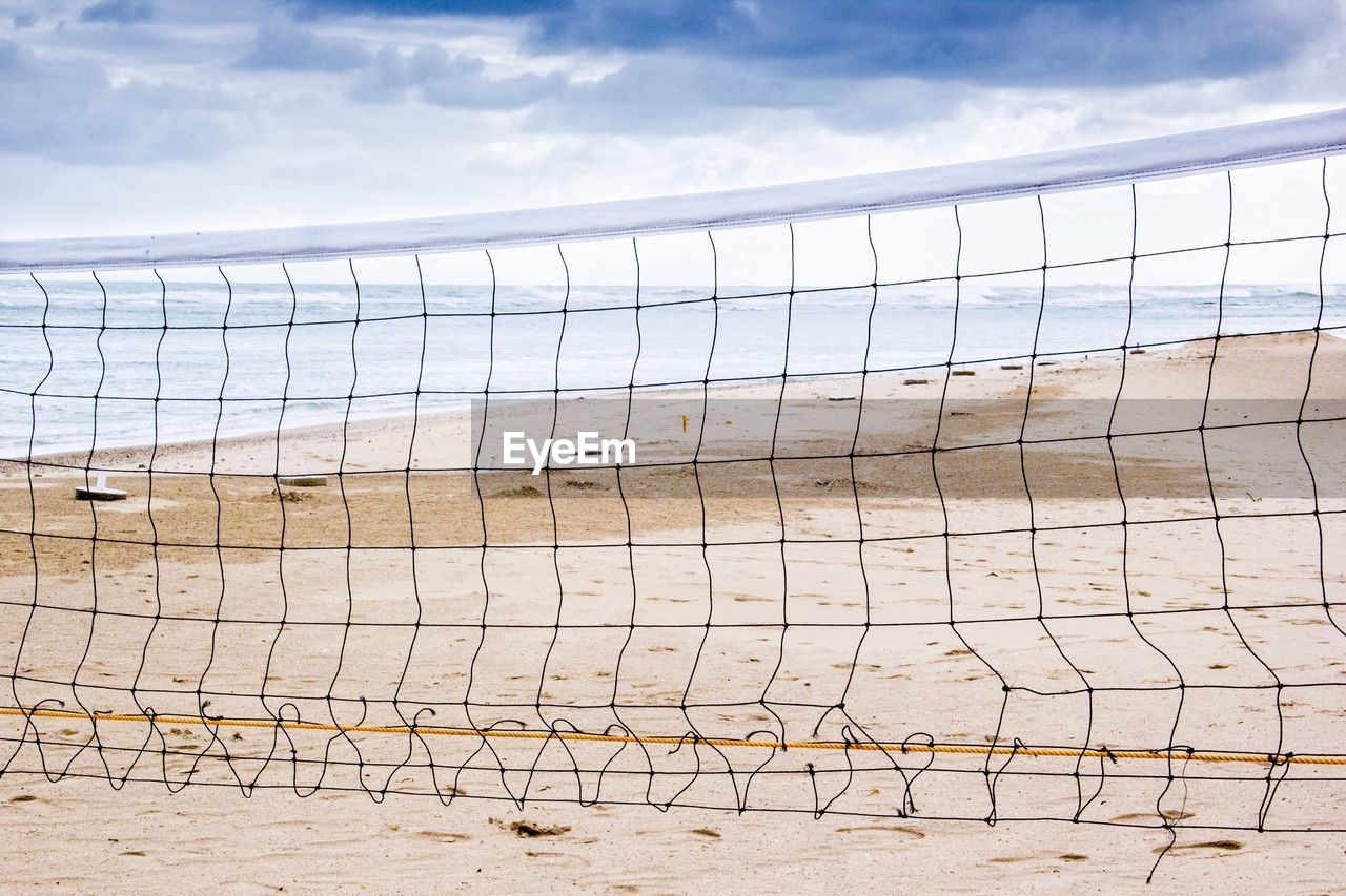 Volleyball net at beach against sky