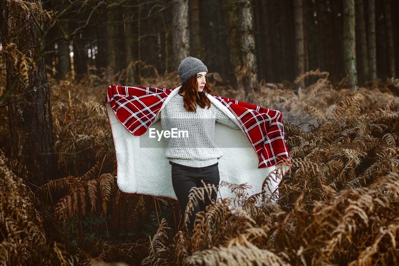 Woman with blanket standing on field during winter