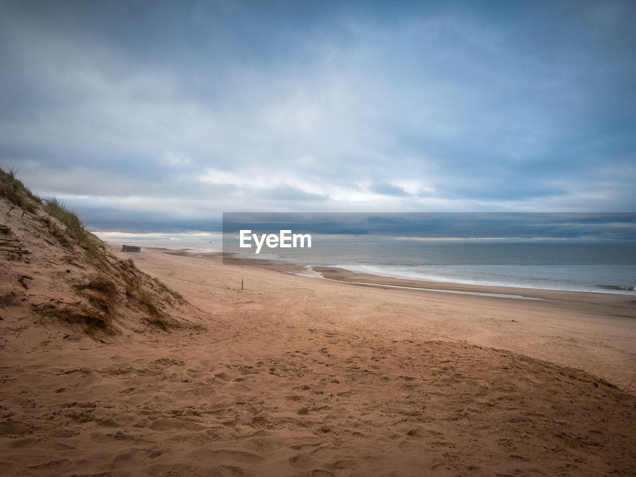 Scenic view of beach against cloudy sky