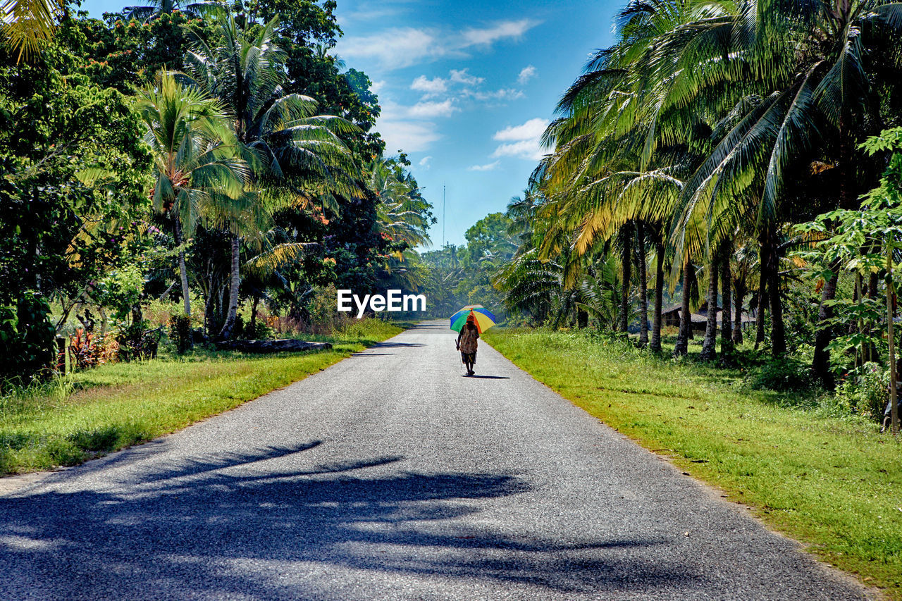 REAR VIEW OF PERSON WALKING ON ROAD