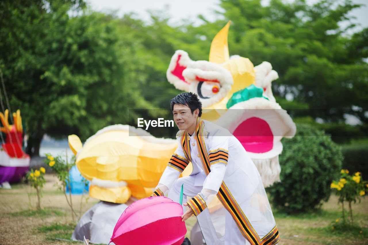 Man in traditional clothing holding toy while standing at park