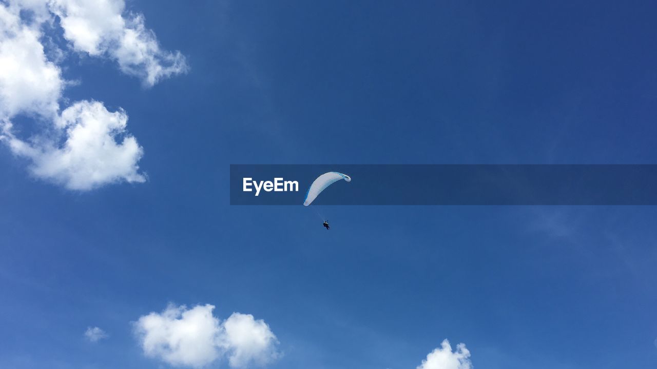 Low angle view of paraglider against blue sky