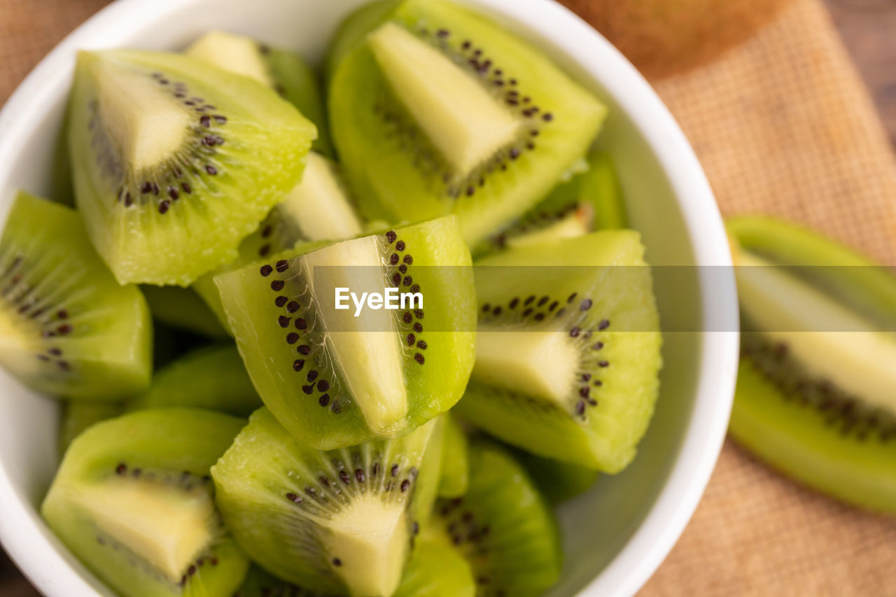 Close-up fresh green kiwi slice in the white bowl on the brown sack