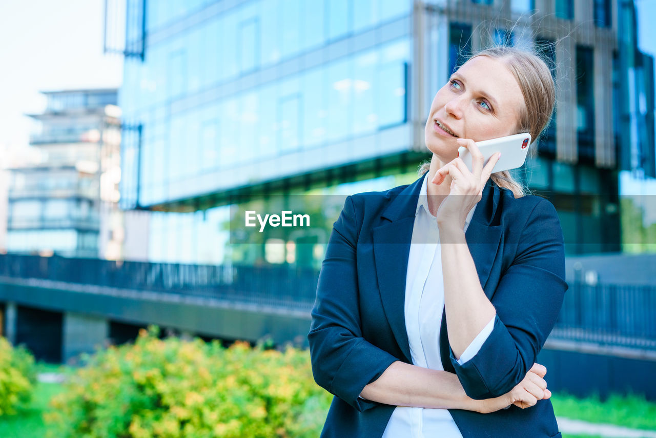 Business woman with phone near office. portrait beautiful smiling girl