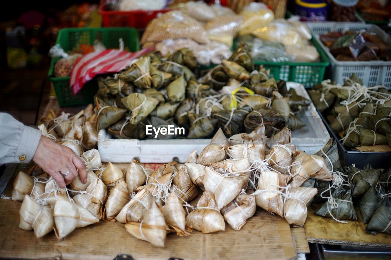 Cropped hand of man buying zongzi at market stall
