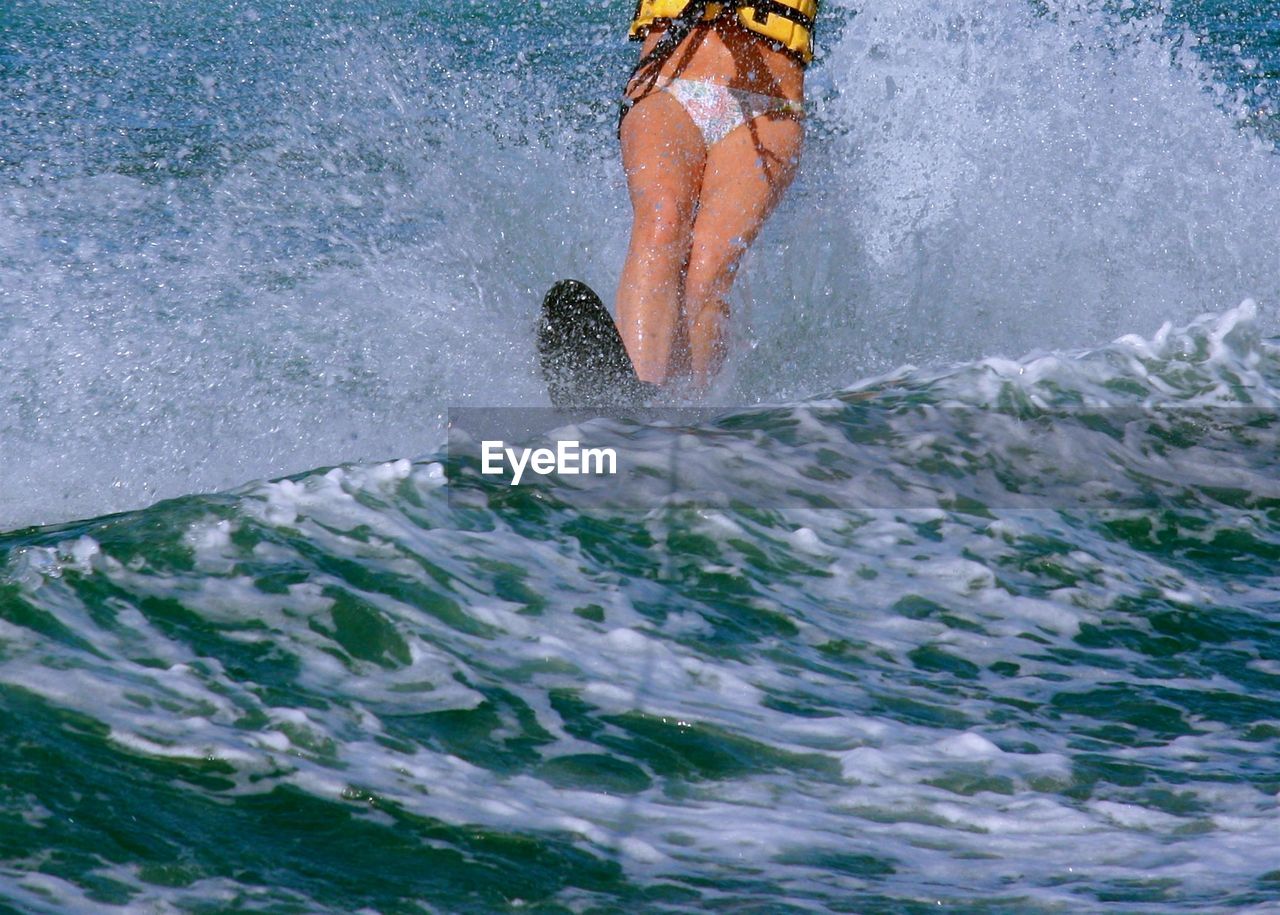 Low section of man splashing water in sea