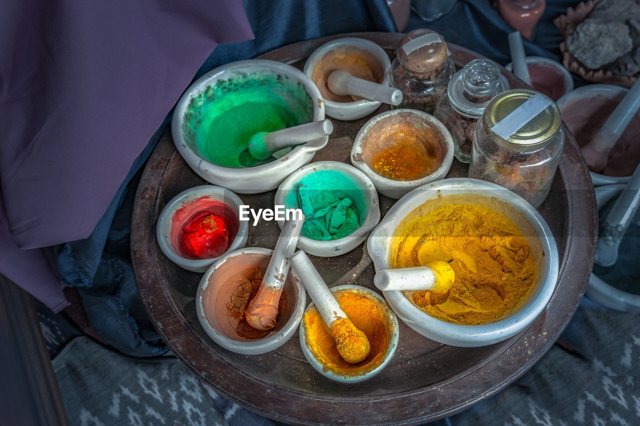 High angle view of powder paints in mortar and pestles on table