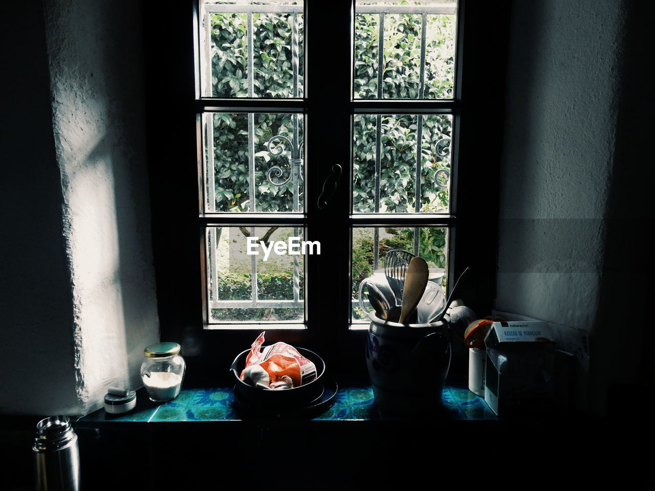 Spatulas in container on window sill at kitchen