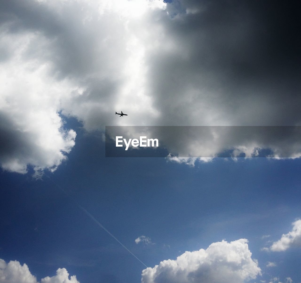 Low angle view of airplane flying against cloudy sky