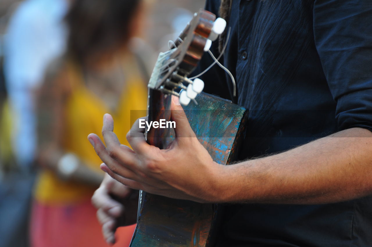 music, adult, midsection, arts culture and entertainment, focus on foreground, holding, hand, musical instrument, musician, performance, one person, men, string instrument, skill, guitar, occupation, plucking an instrument, person, musical equipment, close-up