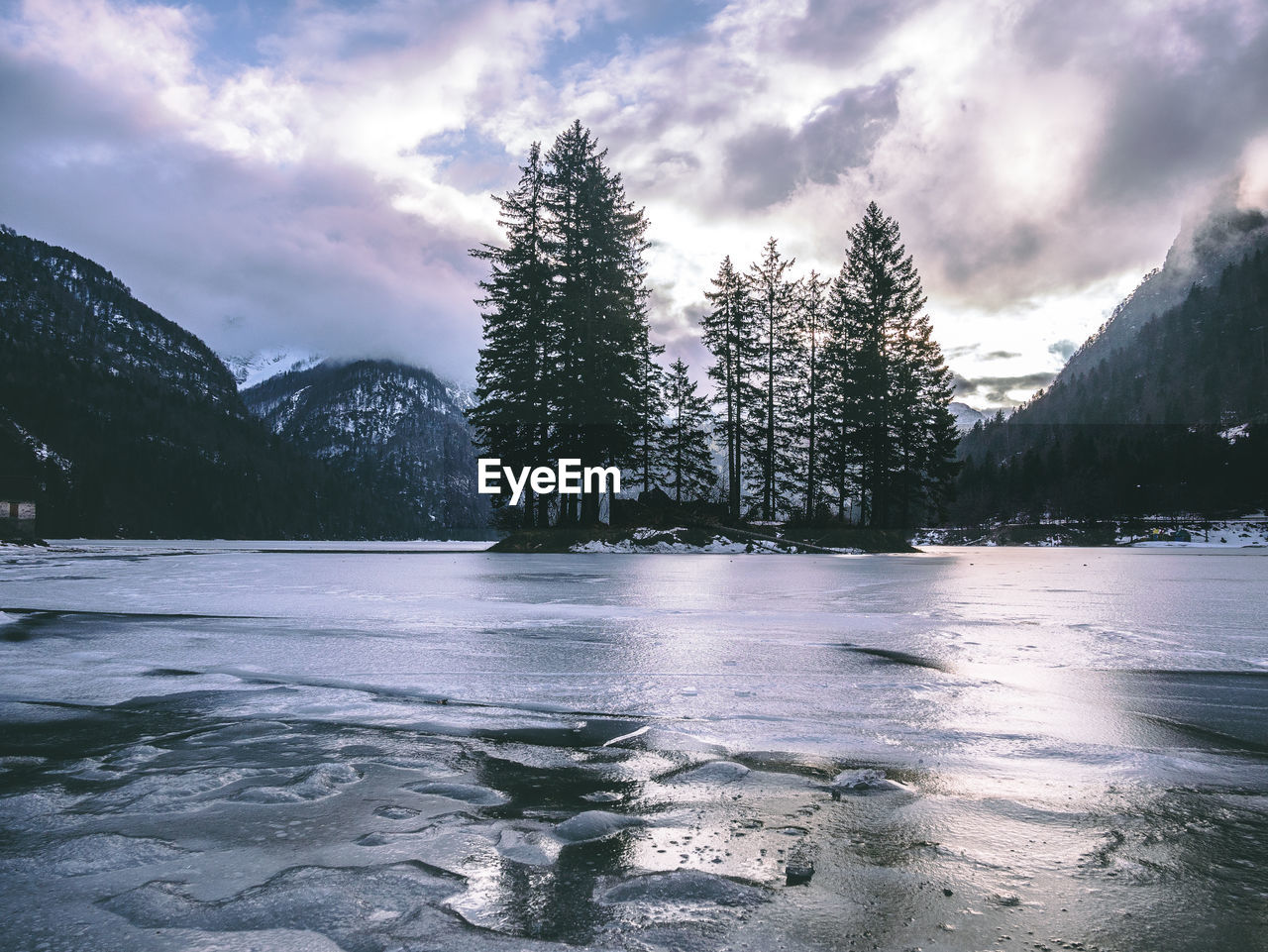 Frozen lake against mountains and sky during winter