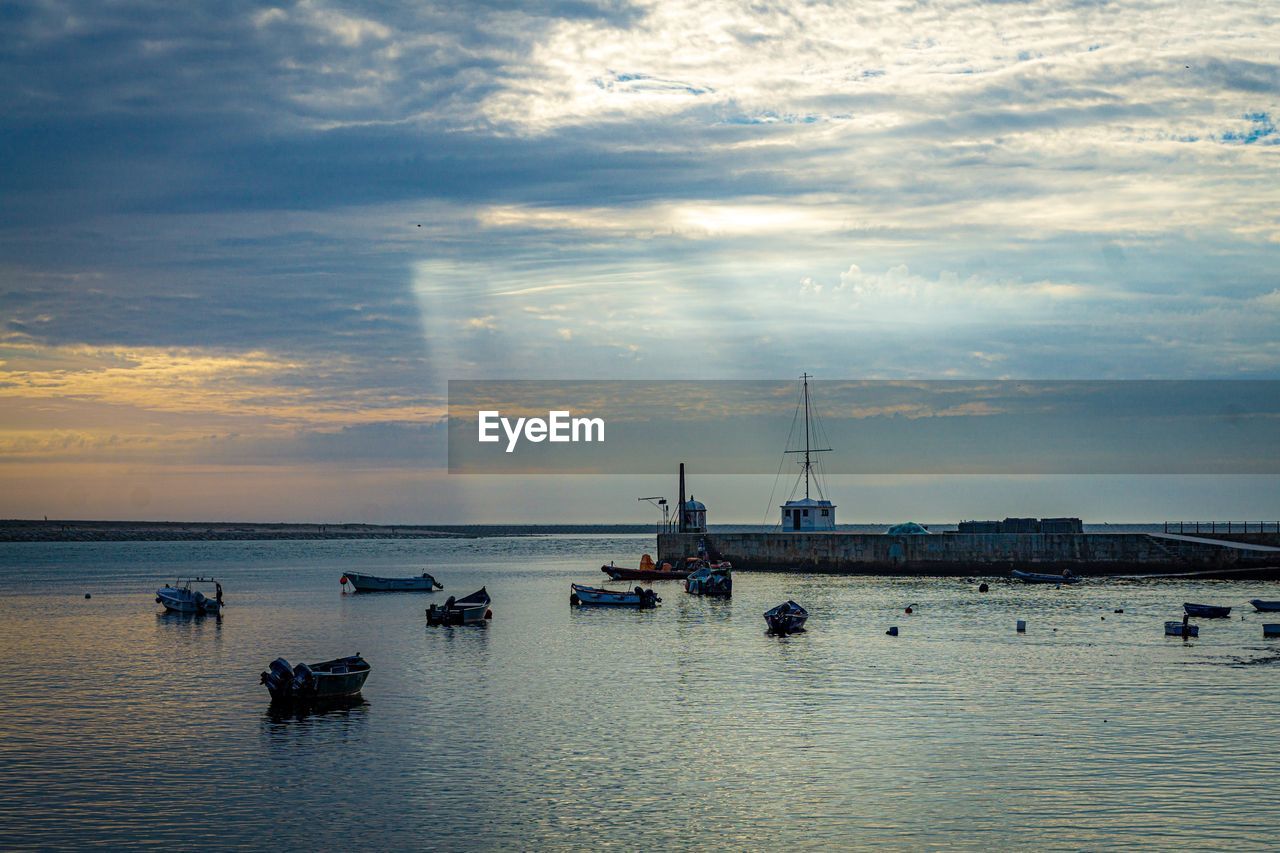 Sailboats in sea against sky at sunset