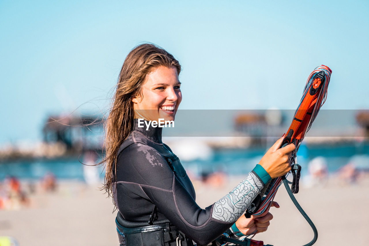 portrait of smiling young woman standing against sky