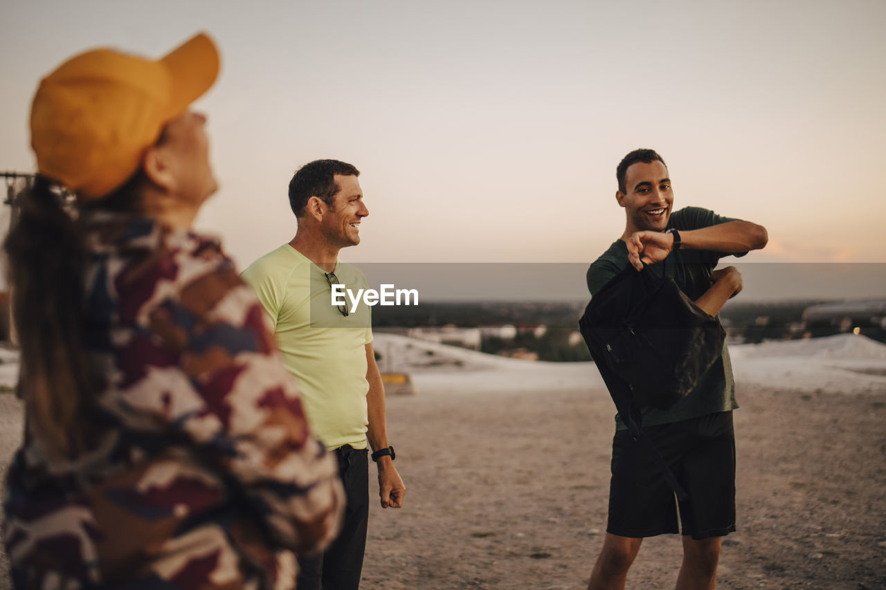 Happy male and female athletes standing on land during sunset