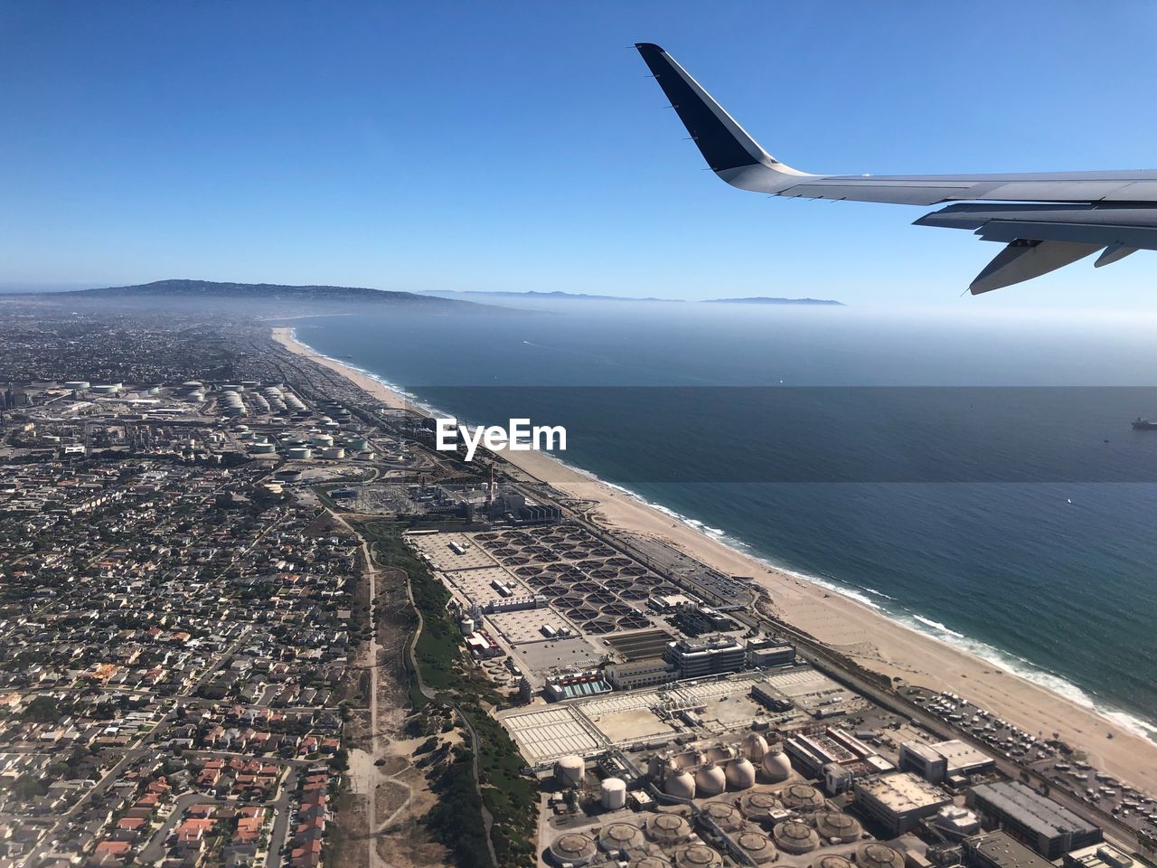 AERIAL VIEW OF SEA BY CITYSCAPE AGAINST CLEAR SKY