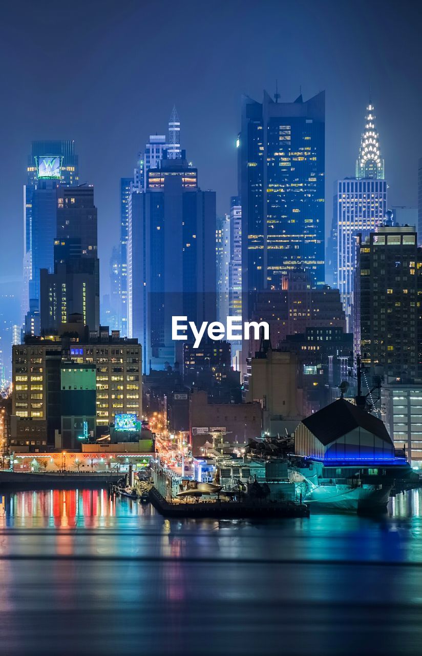 Illuminated buildings by river at night