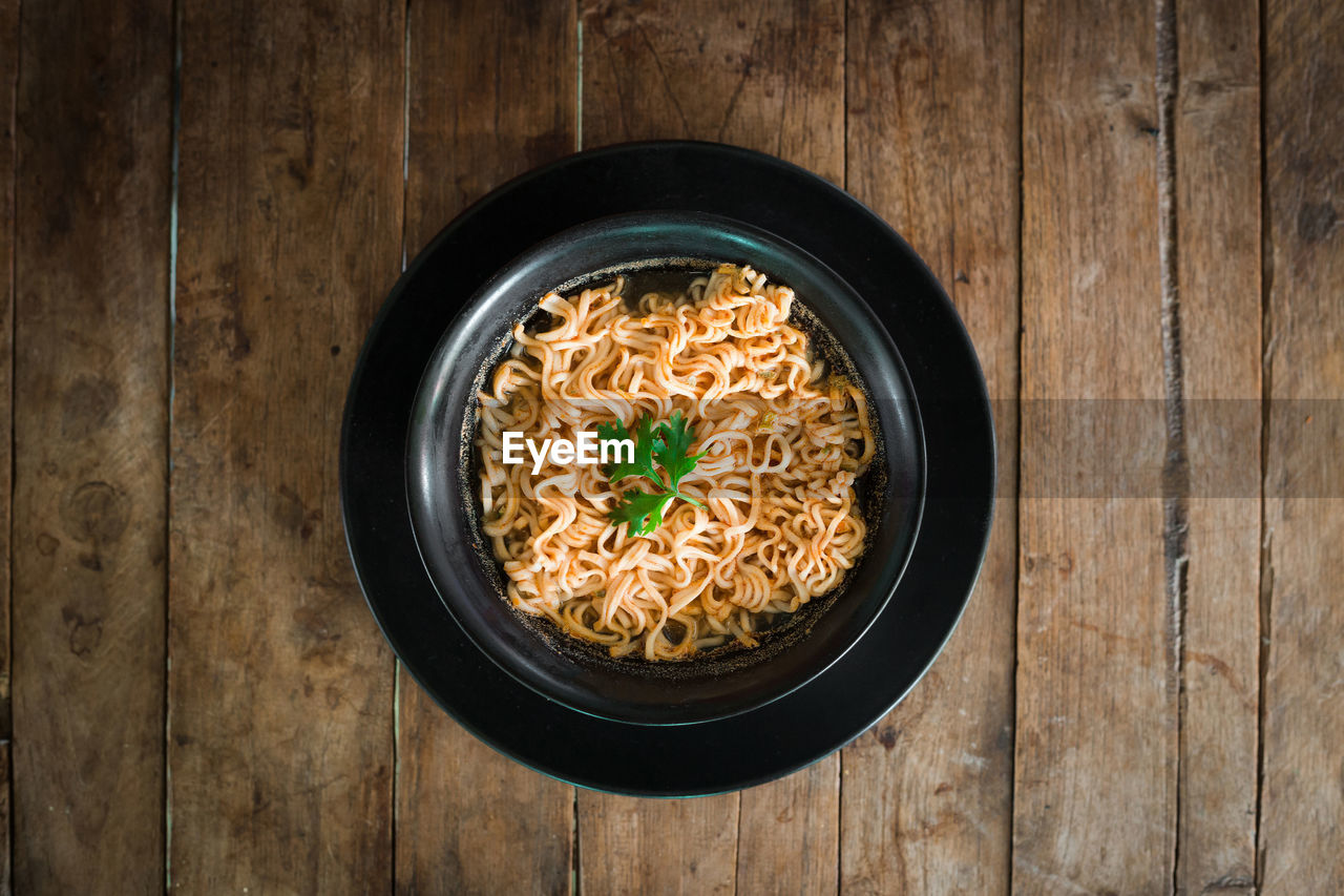 Instant noodles in a cup on the wooden floor, asian meal, 3 minutes, top view