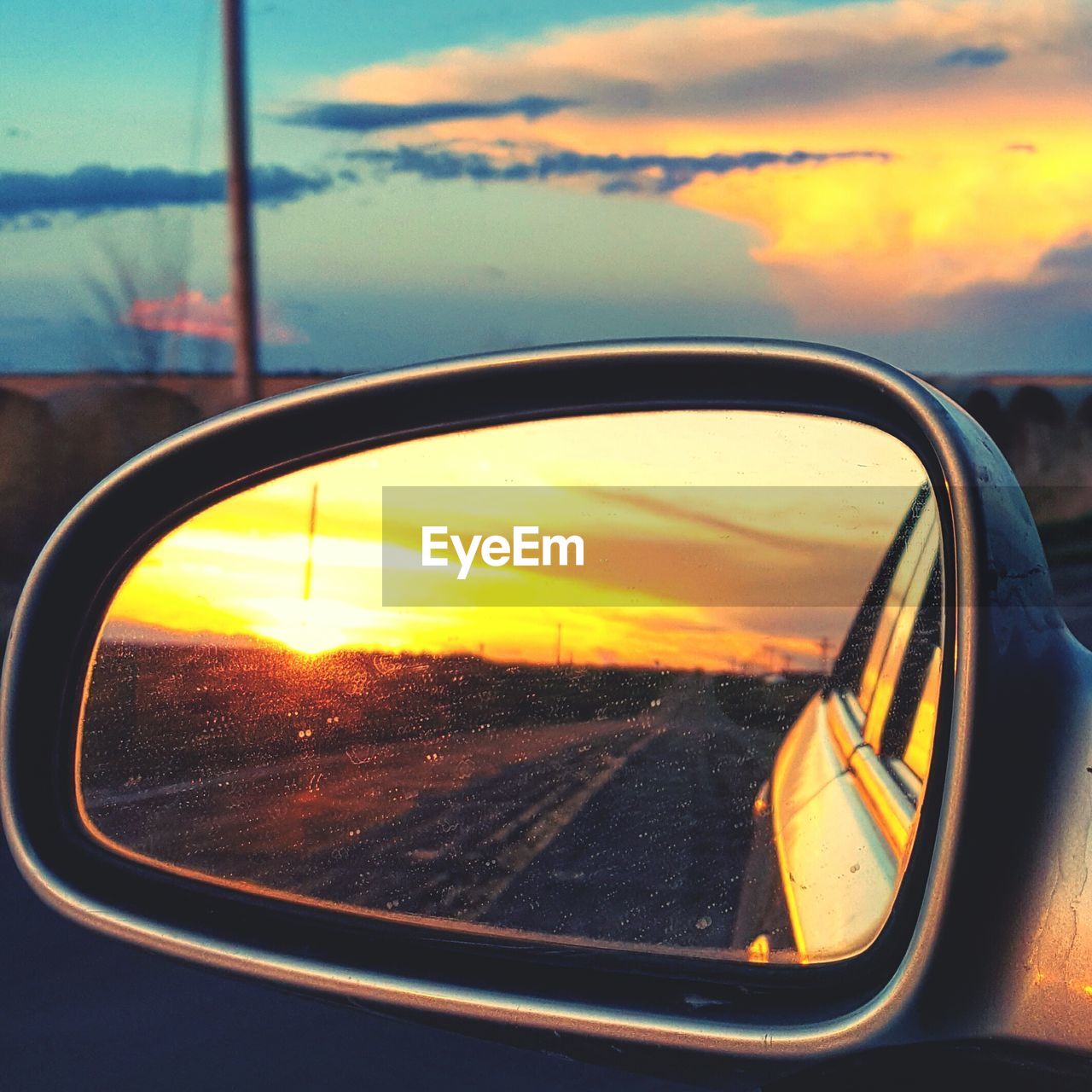 CLOSE-UP OF SIDE-VIEW MIRROR AGAINST SUNSET