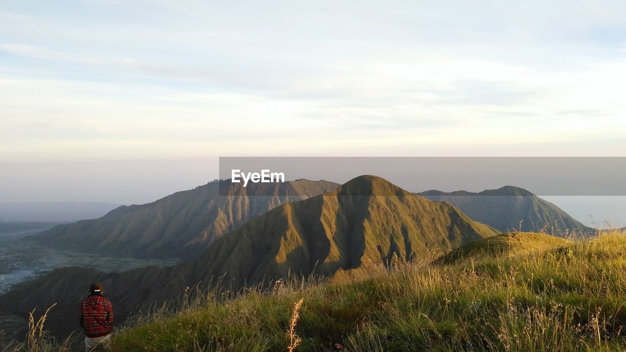 Man looking at mountain range against cloudy sky