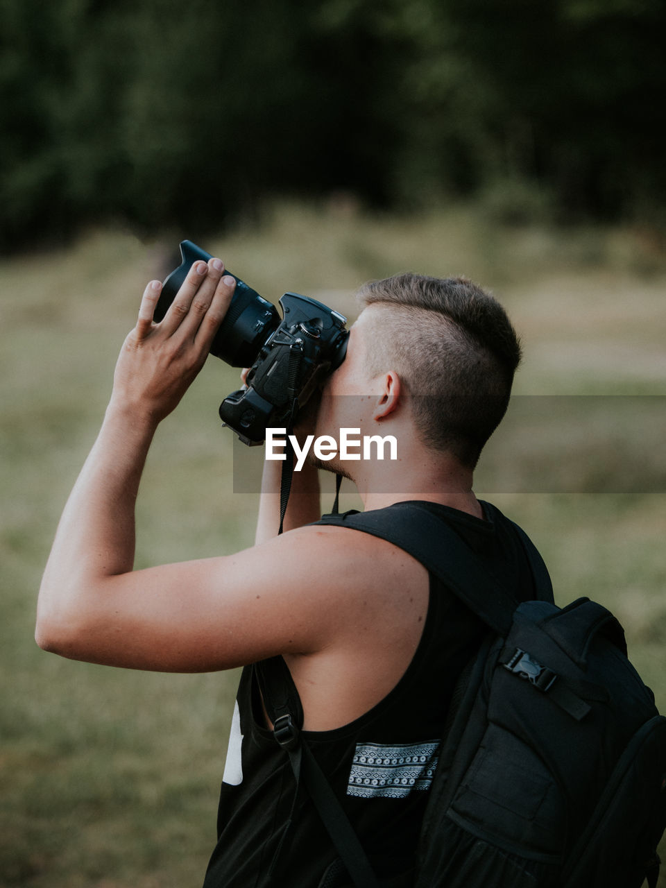 Man photographing with camera on field