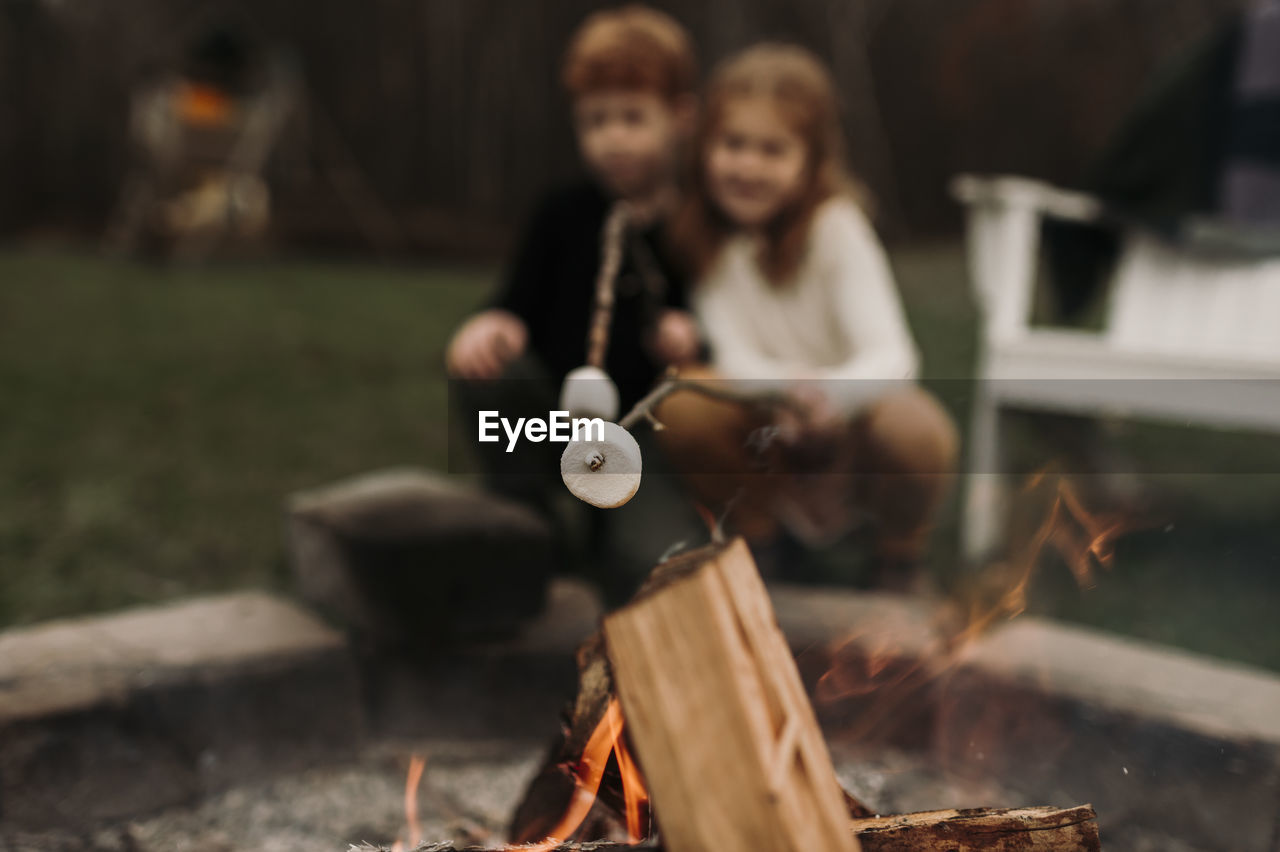 Siblings roasting marshmallows at campfire