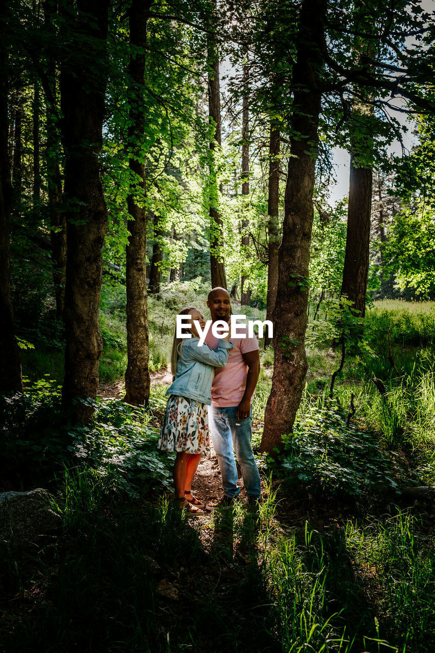 Biracial couple standing and laughing in forest