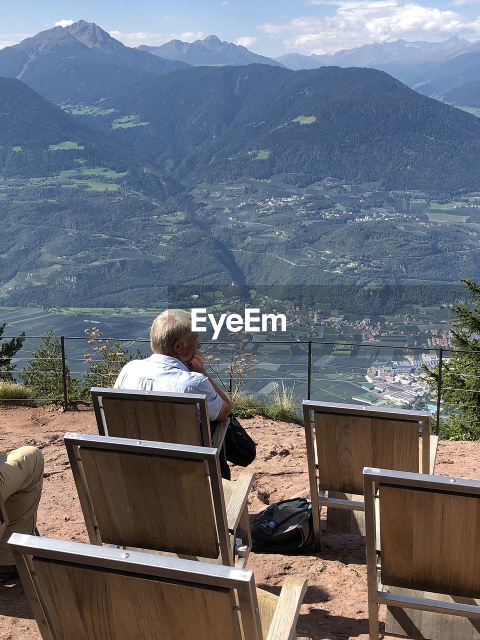 Rear view of woman sitting on shore against mountains