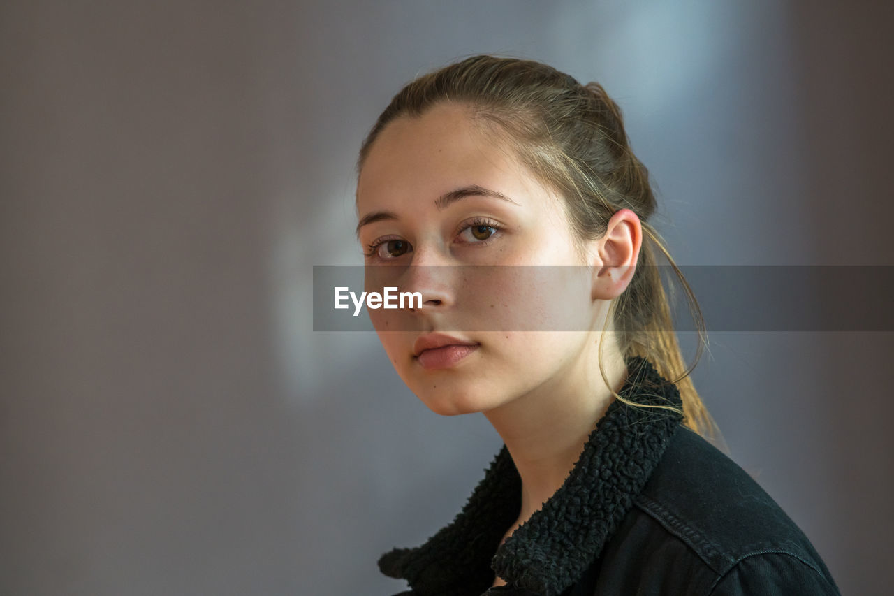 Close up portrait of a pretty teenage girl with ponytail hair and smooth skin looking at the camera