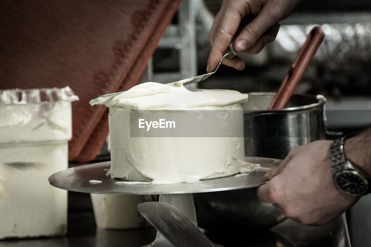 Cropped hands of man making cake in kitchen