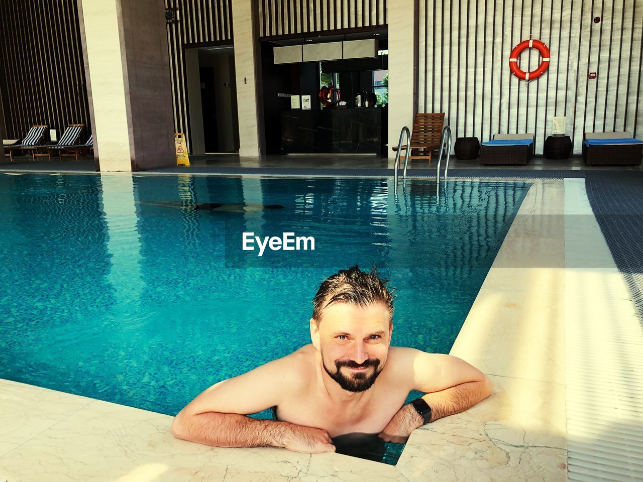 Portrait of smiling shirtless man swimming in pool