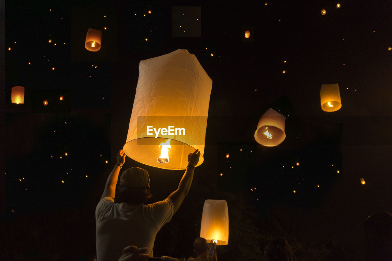 Low angle view of man releasing paper lantern at night