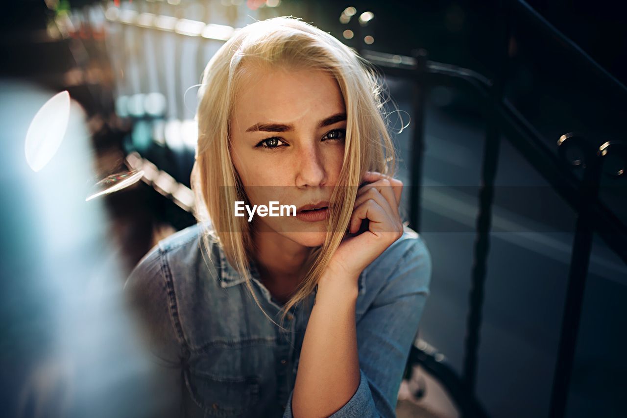 CLOSE-UP OF YOUNG WOMAN USING MOBILE PHONE IN BUILDING