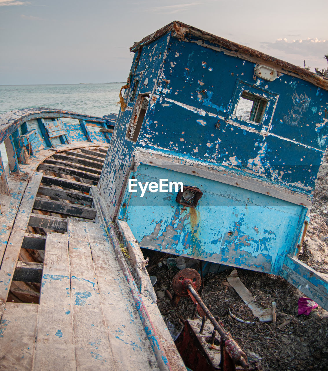 VIEW OF ABANDONED BOAT AGAINST SEA