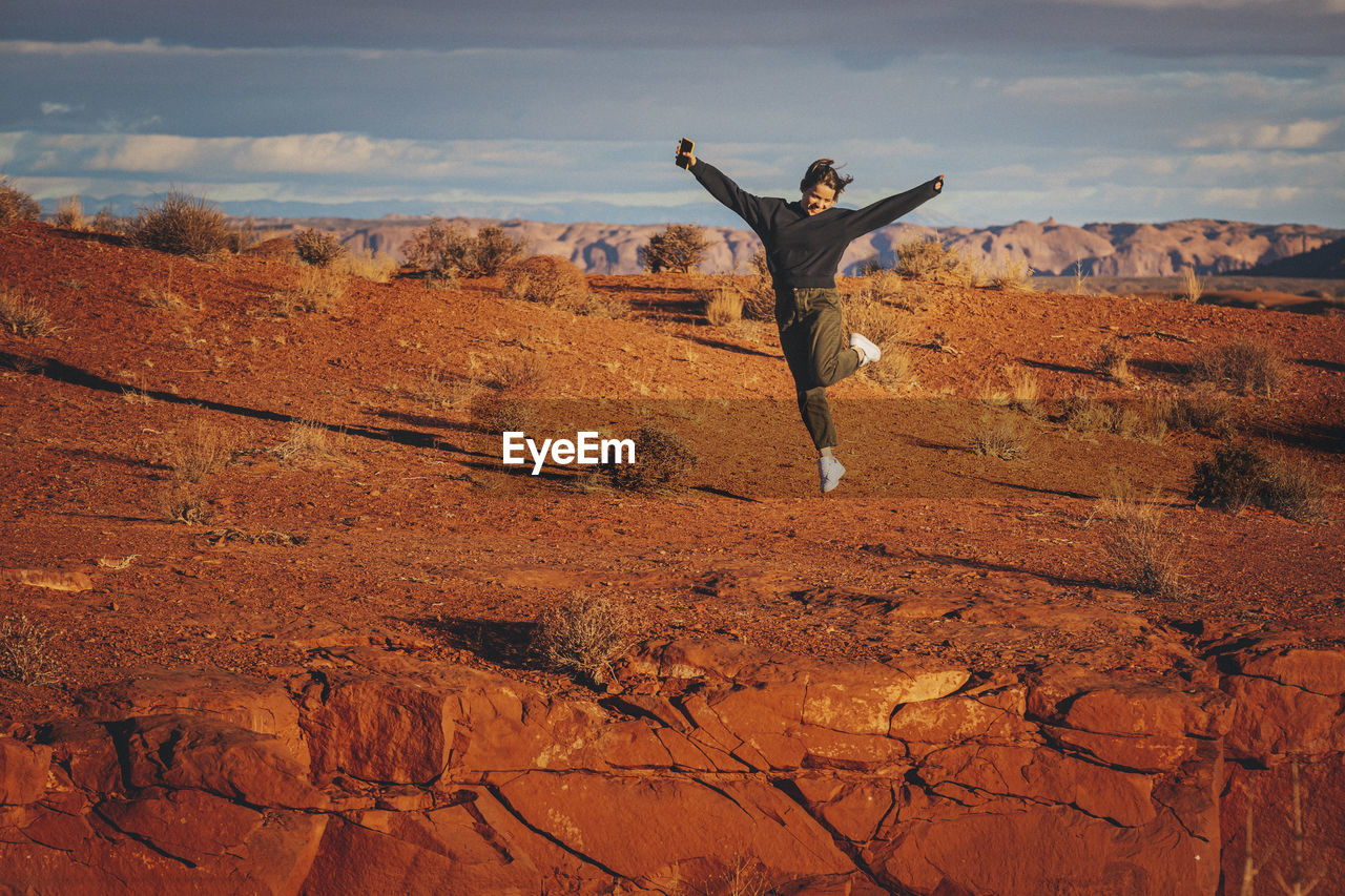 A woman with a phone is jumping in monument valley, arizona