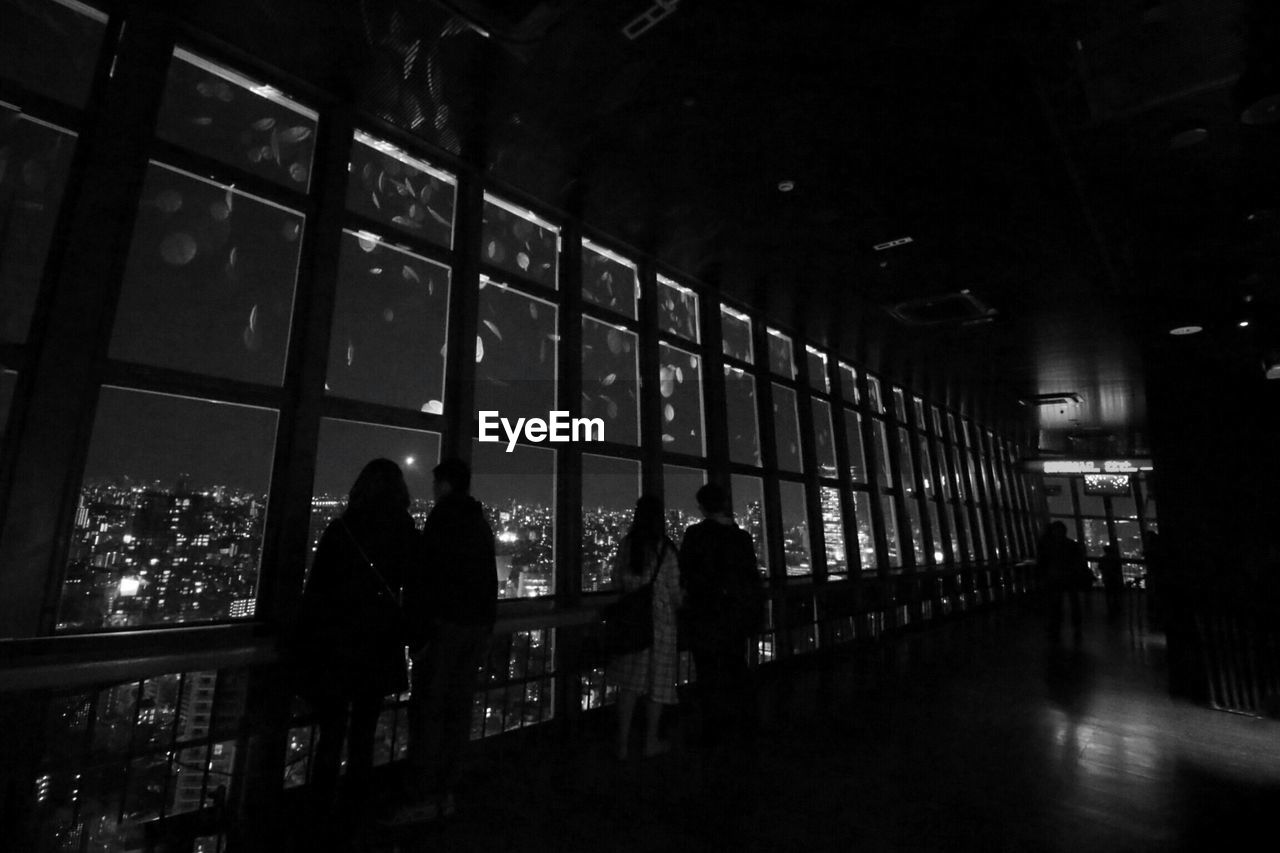 WOMAN WALKING IN ILLUMINATED CITY AT NIGHT