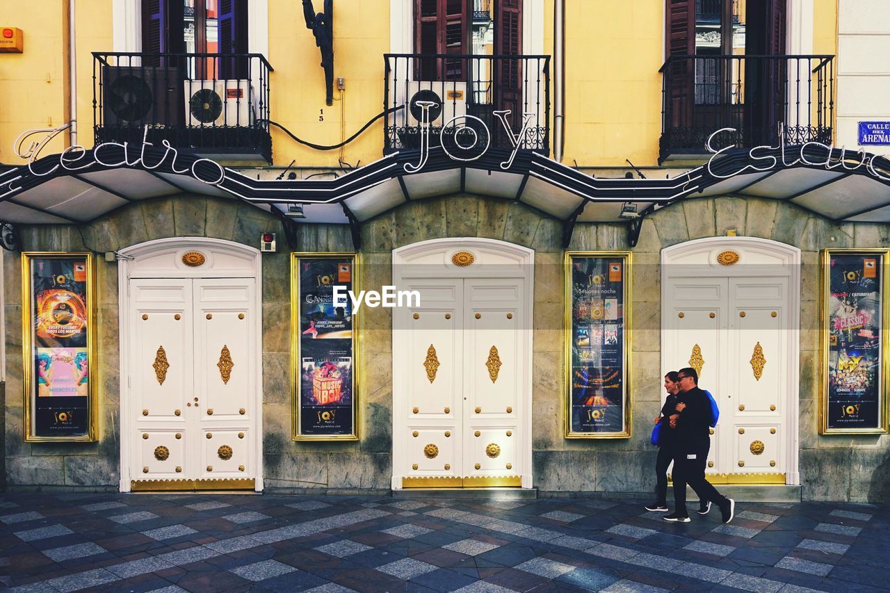 PEOPLE WALKING ON STREET BY BUILDINGS