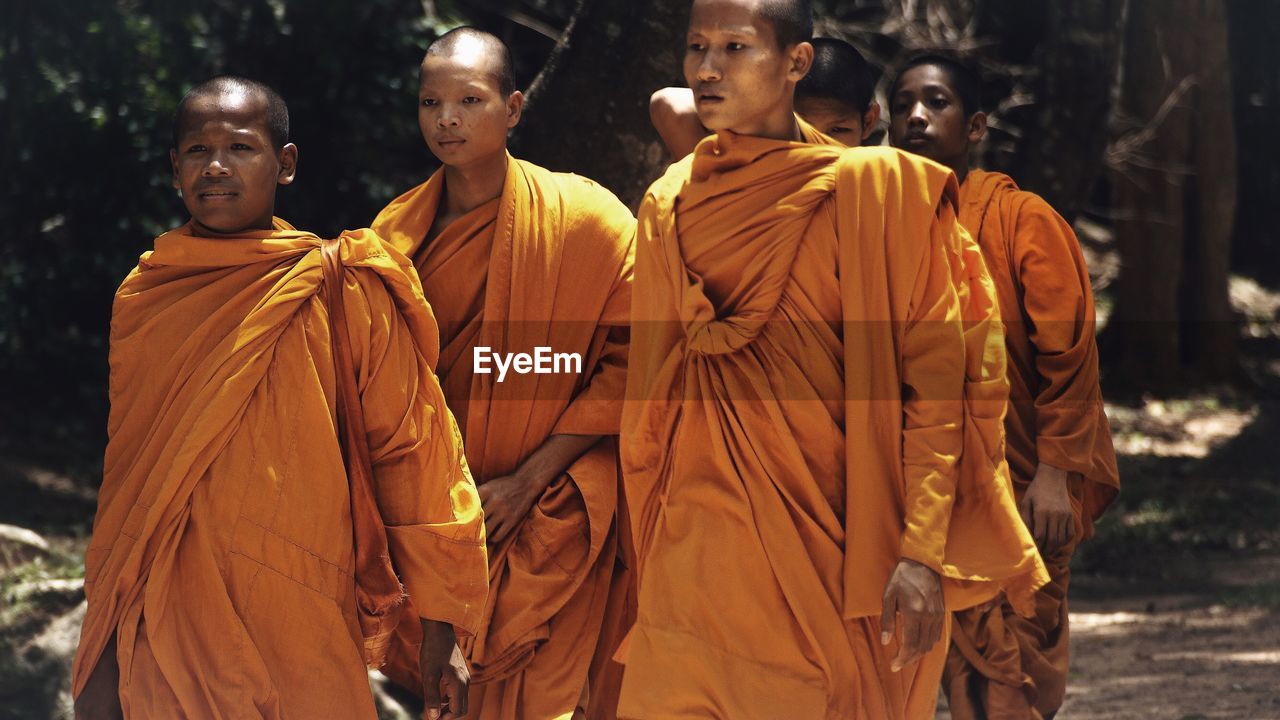 CLOSE-UP OF MEN STANDING AGAINST YELLOW