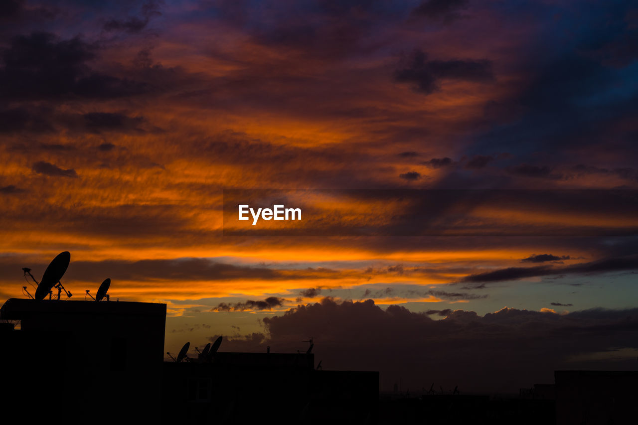 Low angle view of silhouette buildings against orange sky