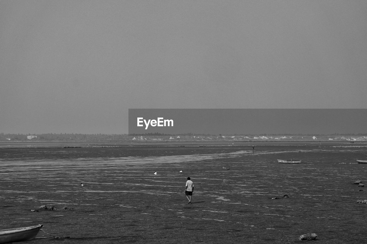 Man on beach against clear sky