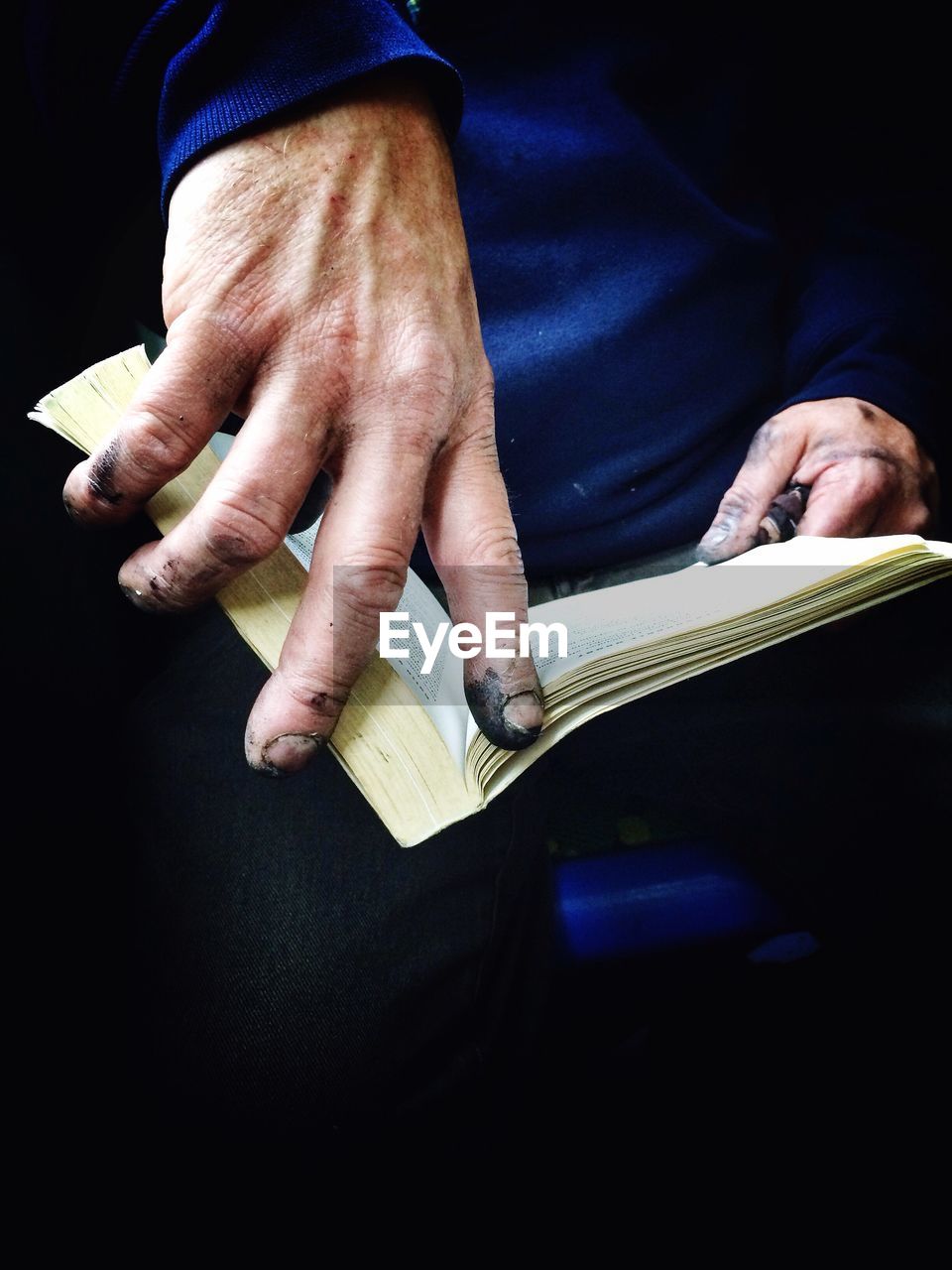Close-up of dirty hands holding book
