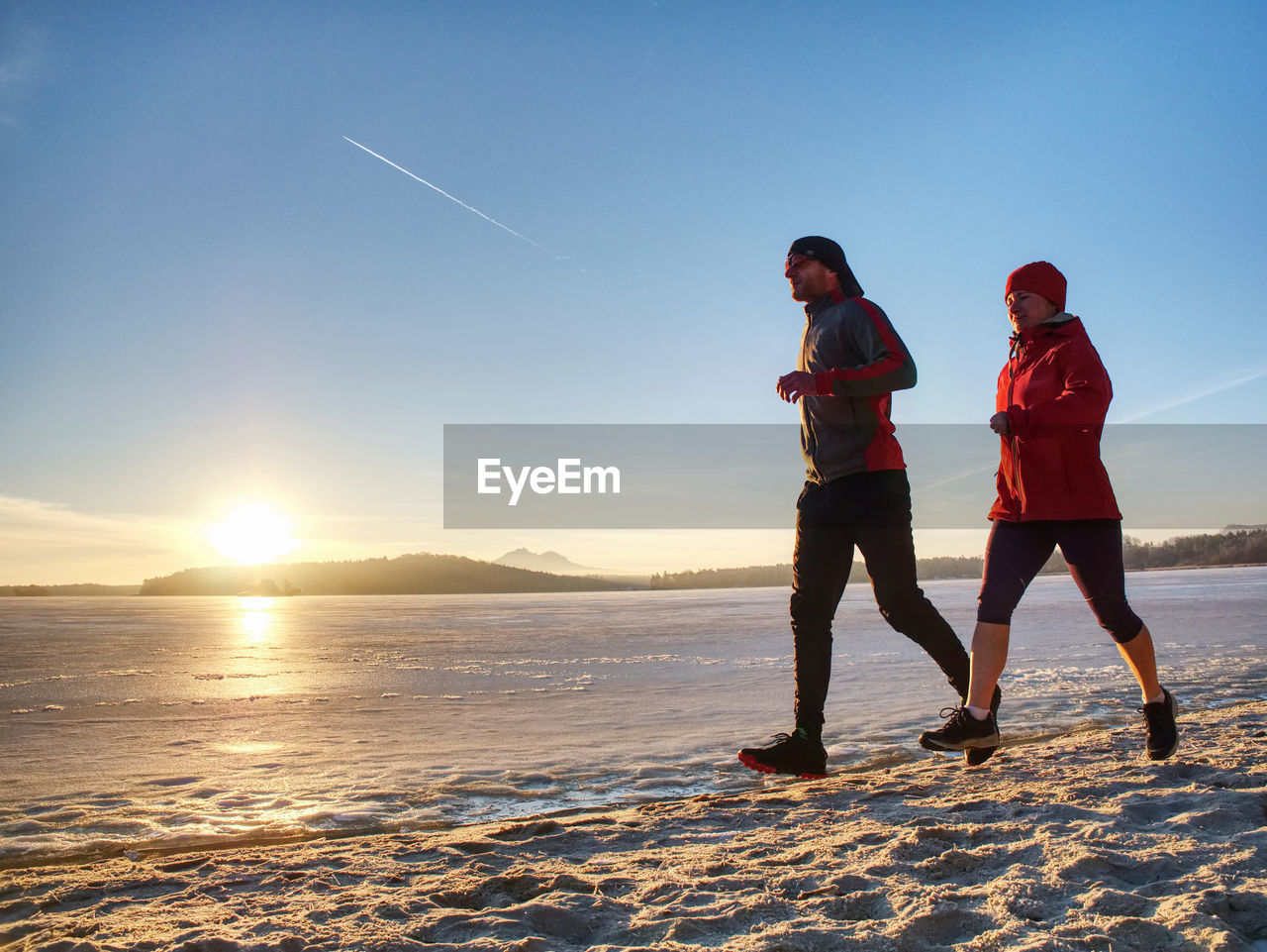 Couple runners running in winter nature. frozen river beach run. copy space.