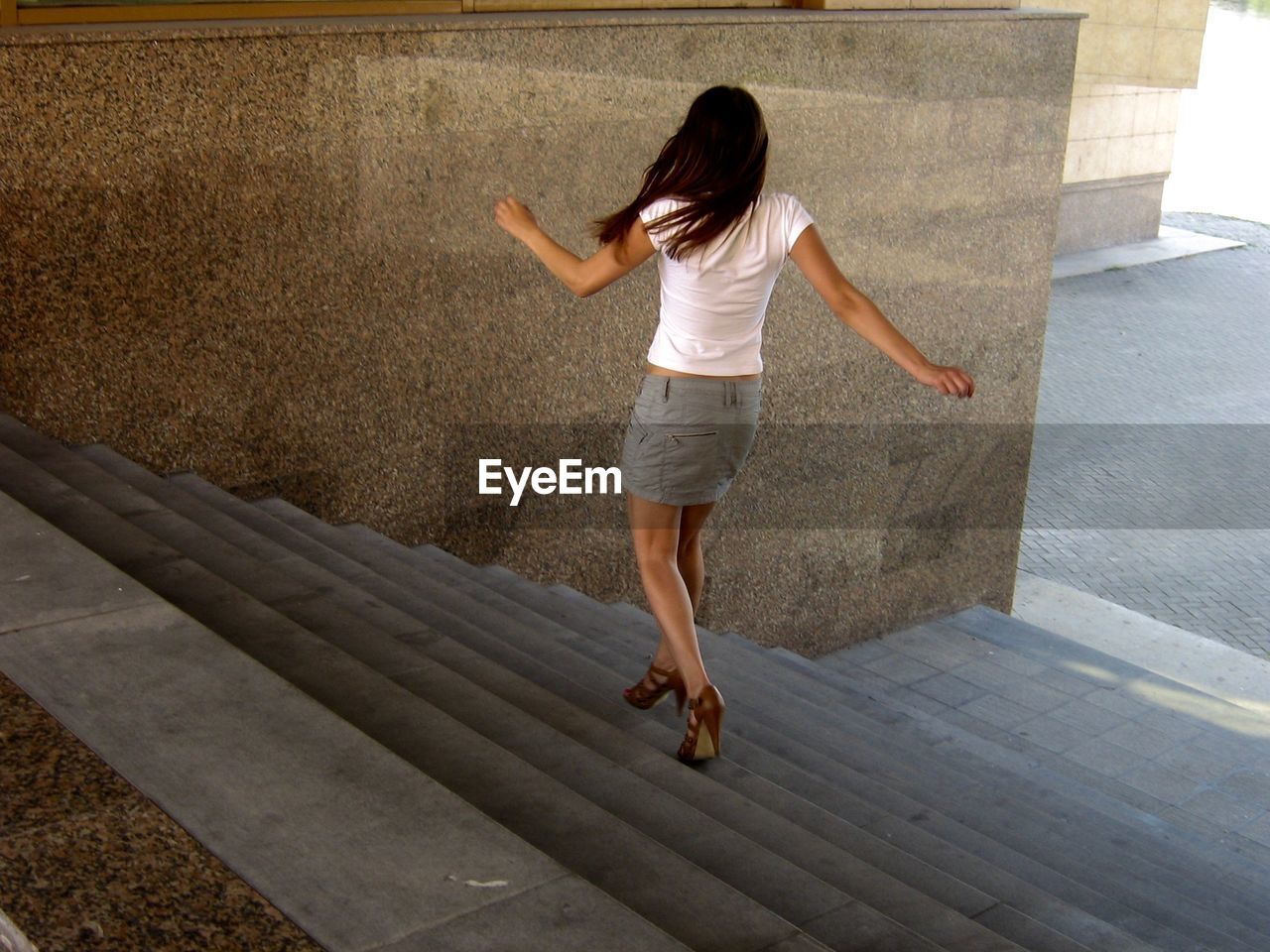 Rear view of young woman moving down on steps