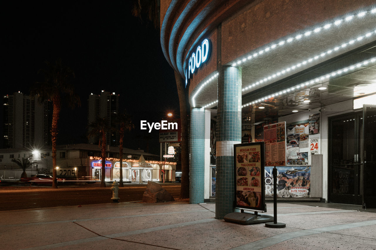 ILLUMINATED STREET BY BUILDINGS AT NIGHT