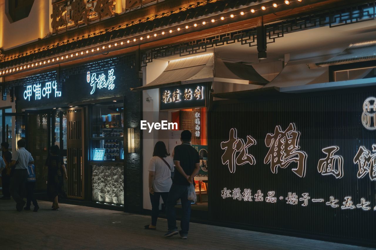 PEOPLE STANDING IN ILLUMINATED STORE