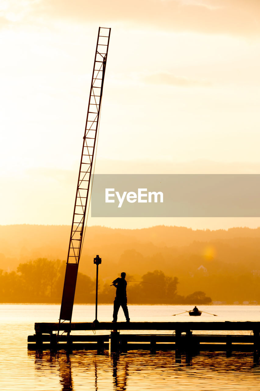 SILHOUETTE MAN STANDING IN SEA AGAINST SKY