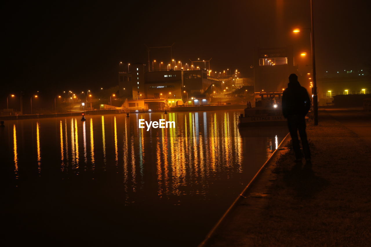 MAN IN ILLUMINATED CITY AT NIGHT